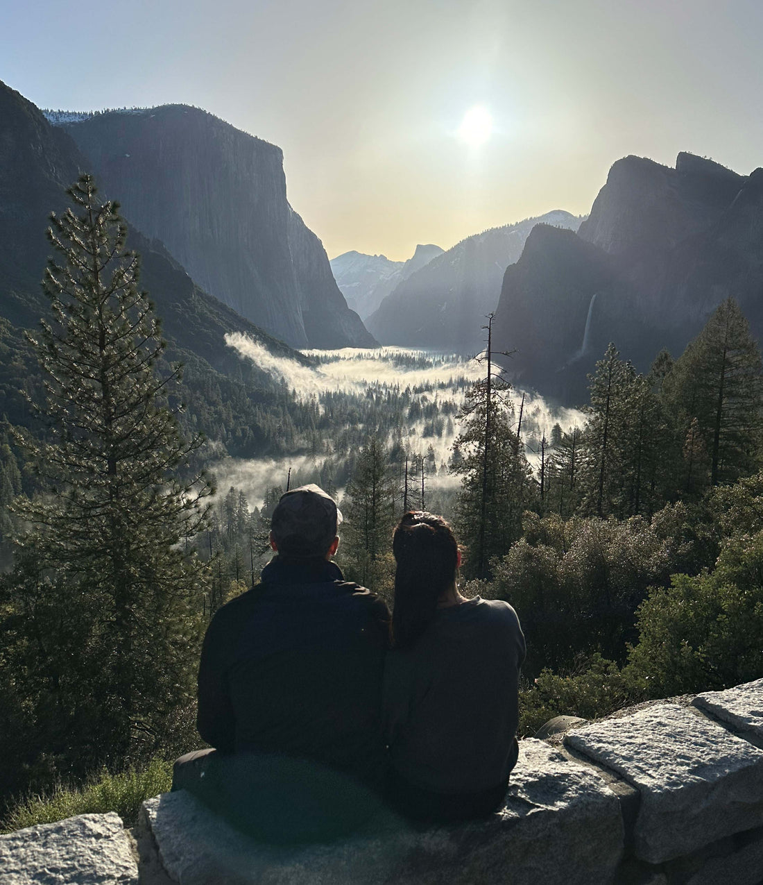 Photo of a couple sitting at the tunnel in Yosemite National Park watching the sunrise over the valley
