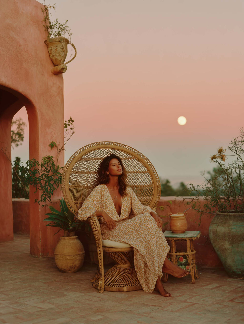 Cosmic Creator Stock Images: Woman in long floating dress sitting on a tuscan inspired balcony in a rattan peacock chair as the moon rises behind her, spiritual coach stock images